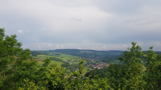 Grüne Landschaft im Mittelgebirge. Im Tal liegt ein kleines Dorf.
