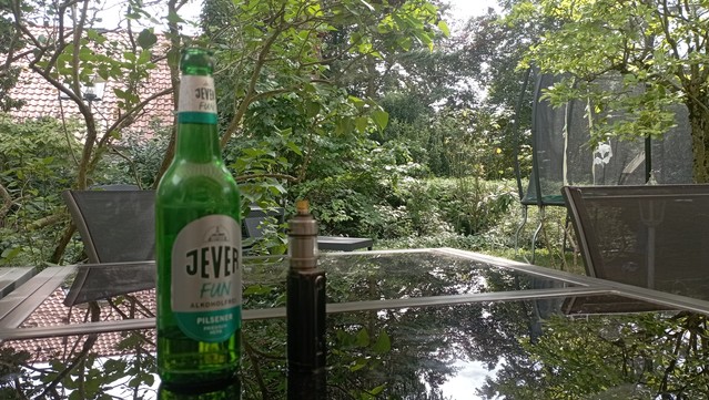 Auf dem Gartentisch eine Flasche alkoholfreies Bier und das Dampfgerät.